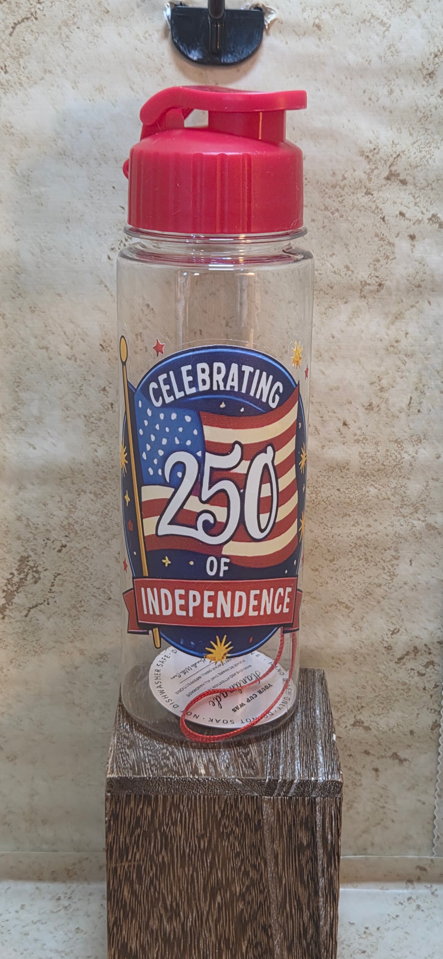 17 ounce clear water bottle with red flip top lid and strap with Celebrating 250 of independence