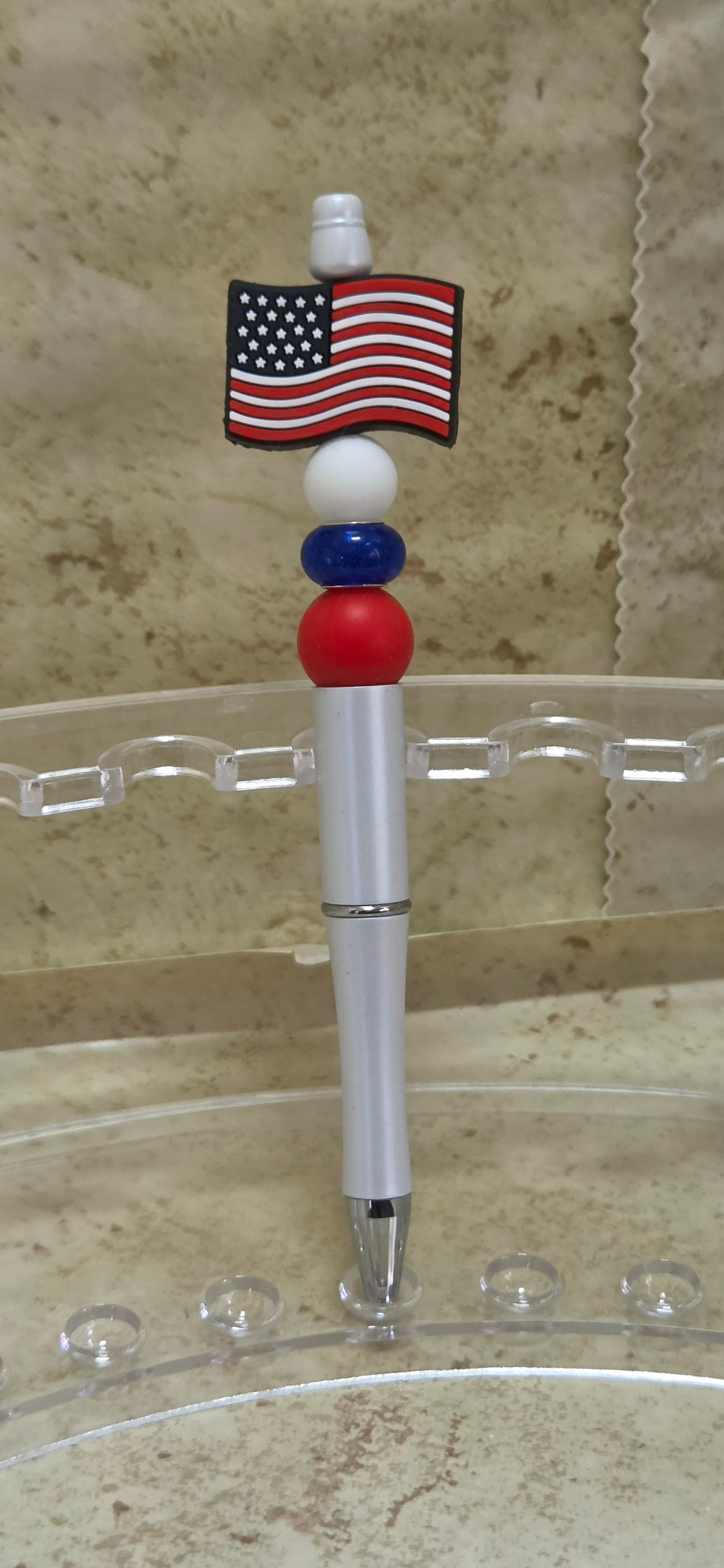 White barreled ball point pen with red white and blue beads and a silicone flag beads on the top