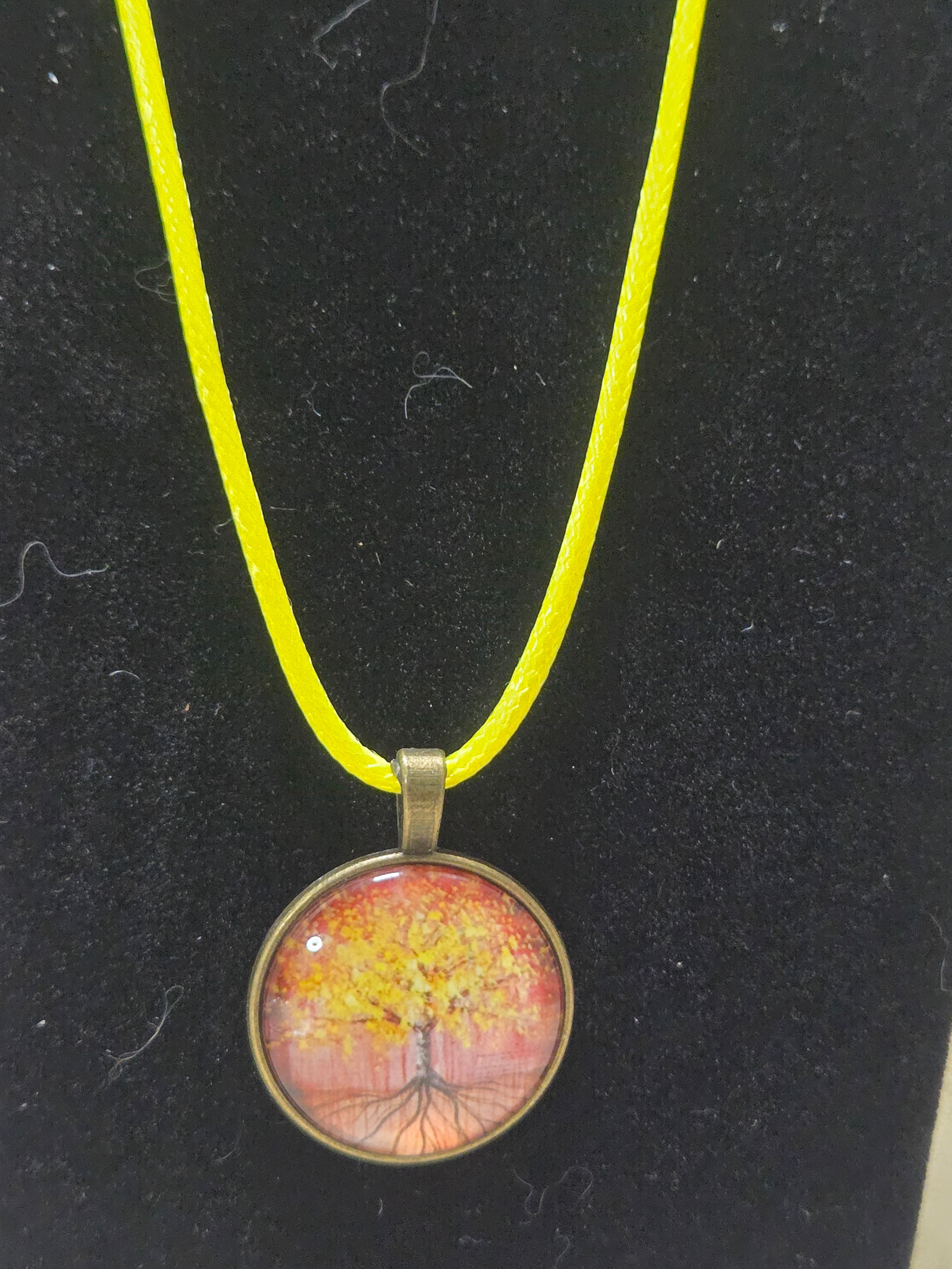 Yellow and orange round necklace with copper back with a tree of life design on yellow leather cord