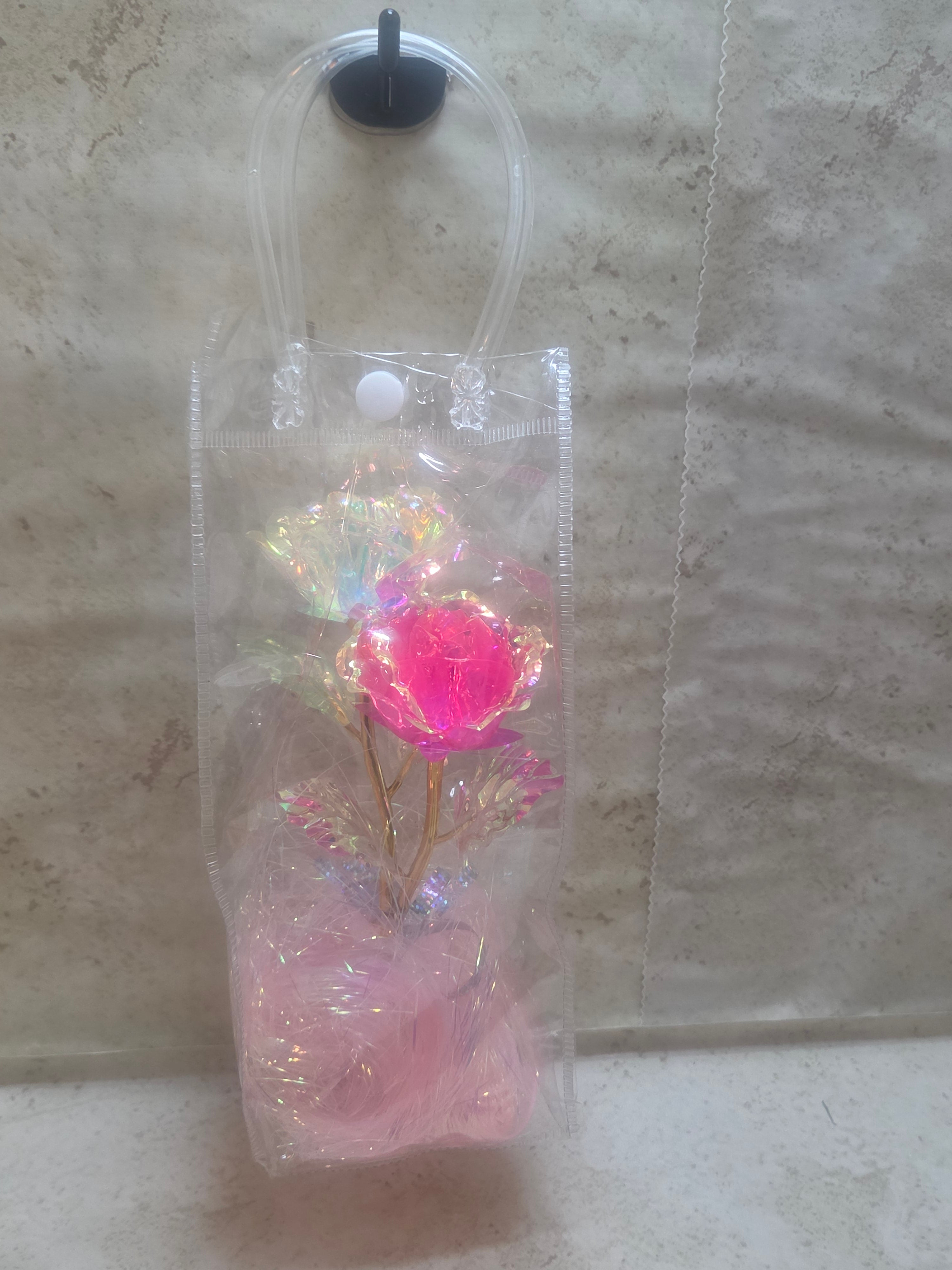12 inch high plastic bag with handles has pink shreds and a pink and white metallic roses inside