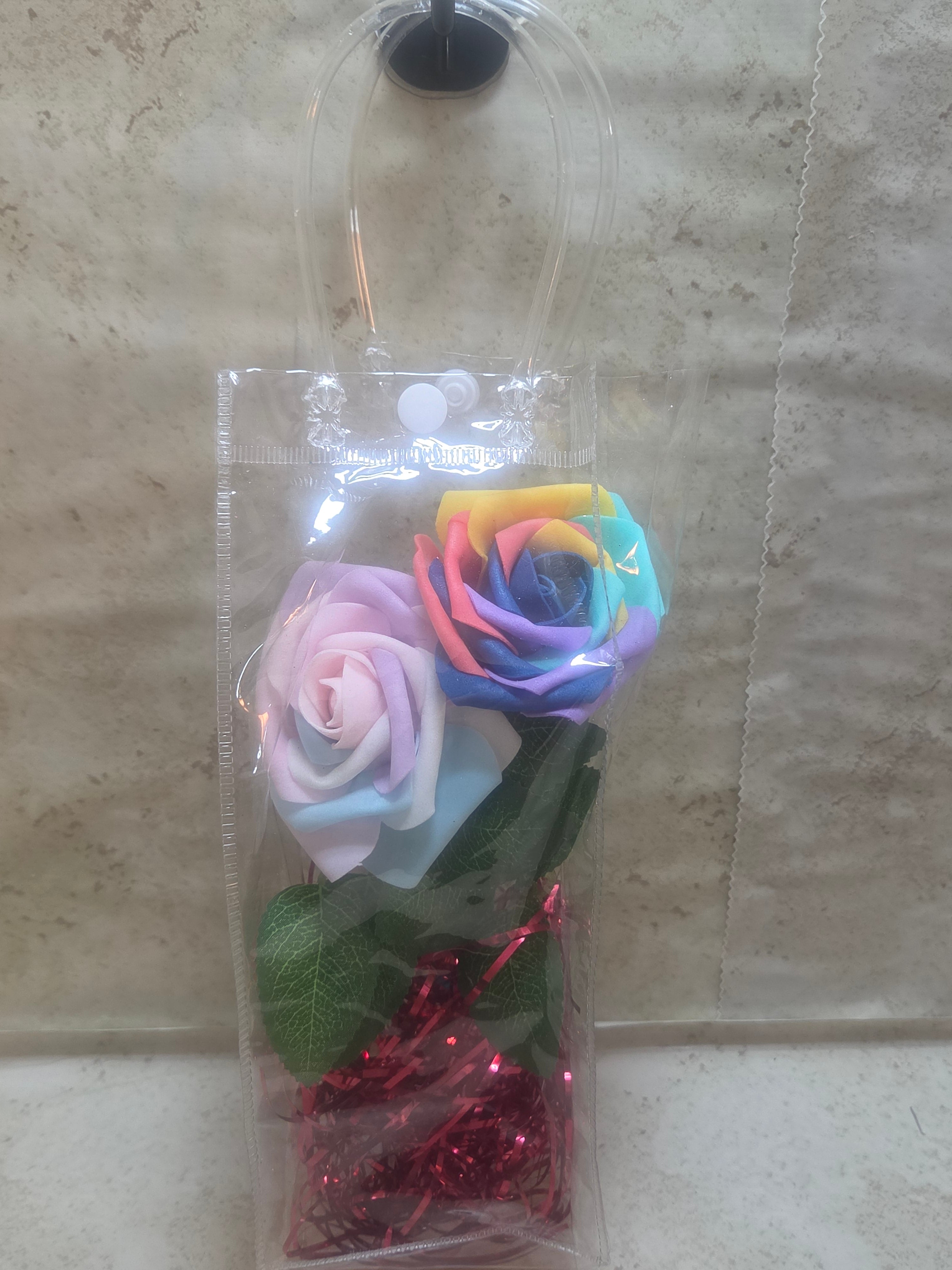 12 inch clear plastic bag with handles has 2 foam roses a gradient and rainbow inside