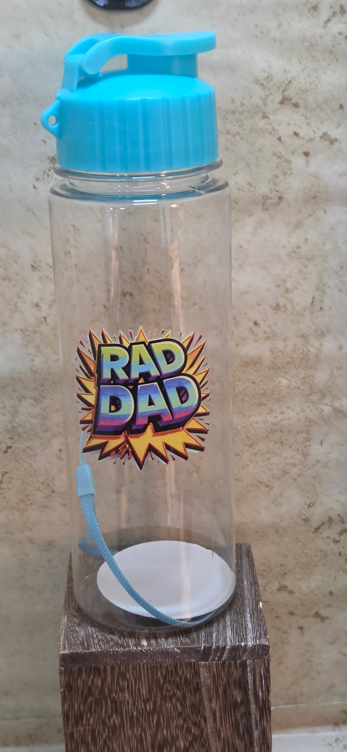 17 ounce clear water bottle with turquoise flip top lid and strap with Rad Dad design on it