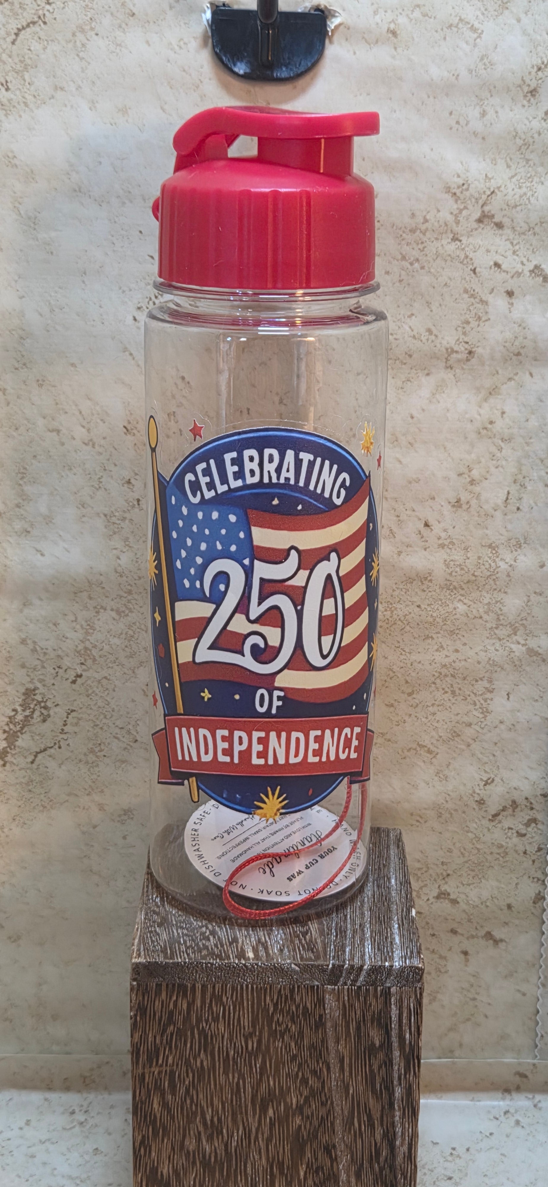 17 ounce clear water bottle with red flip top lid and strap with Celebrating 250 of independence