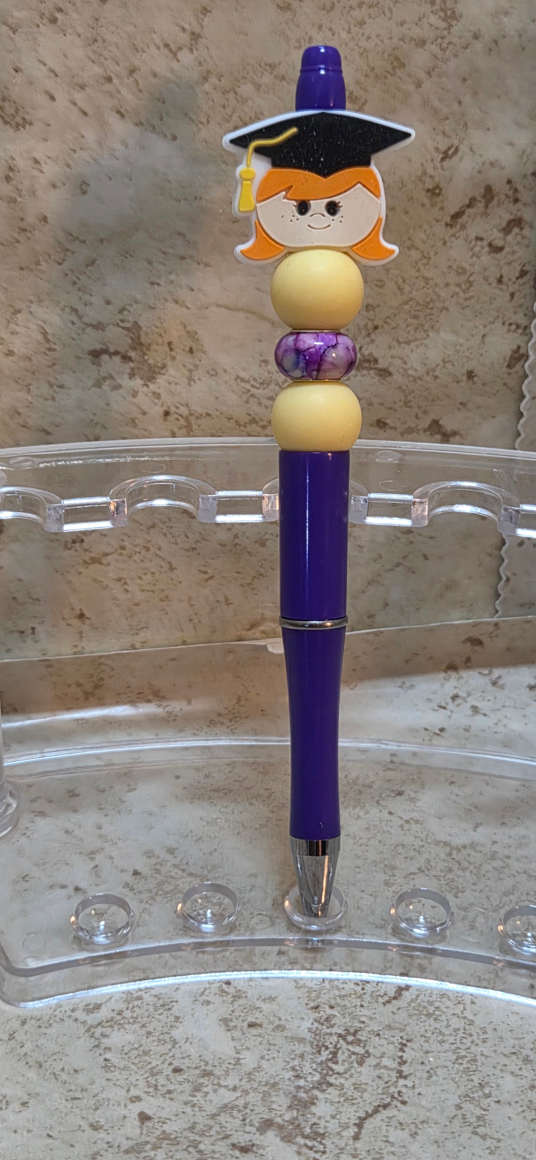 Purple and yellow graduation pen with girl on top