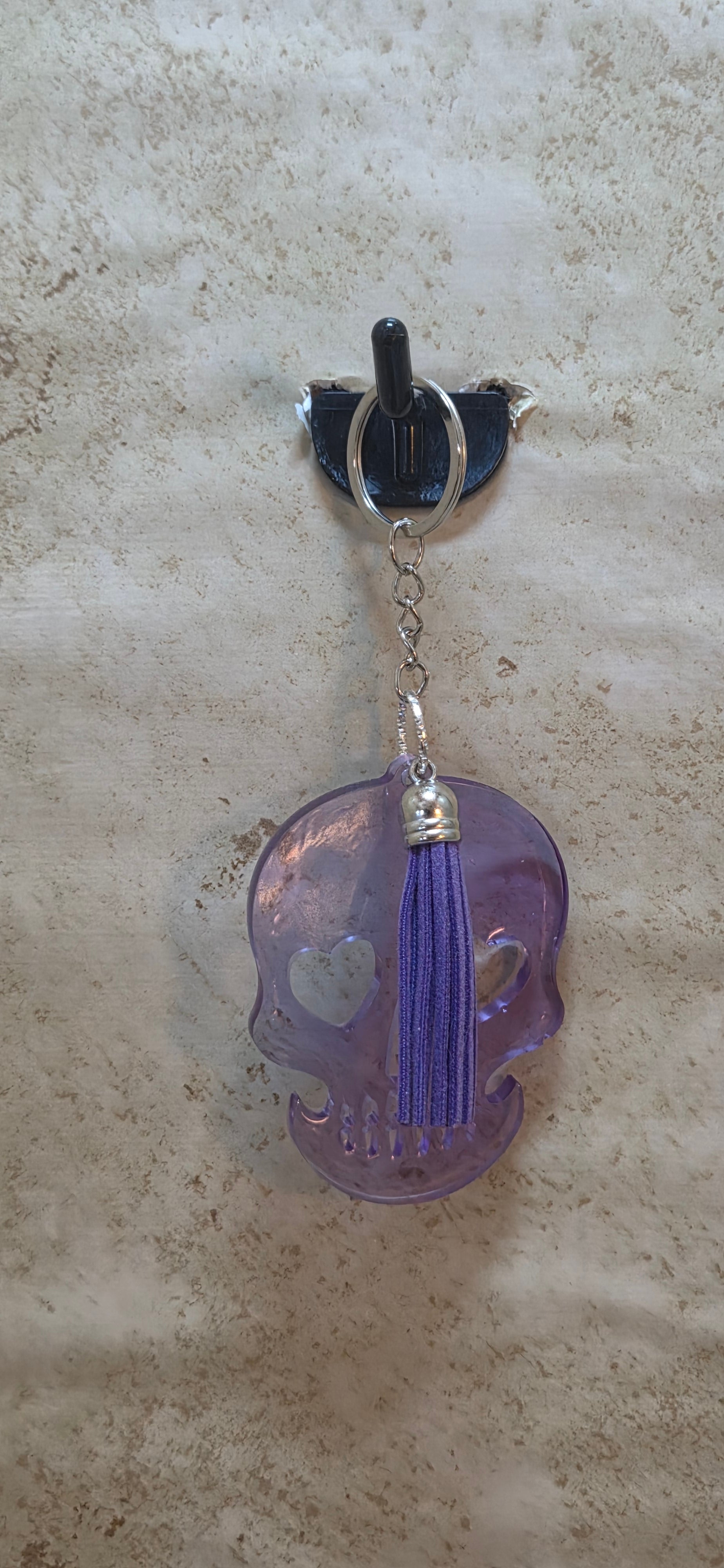 Purple see thru resin skull with hearts cut out for eyes and purple tassel keychain