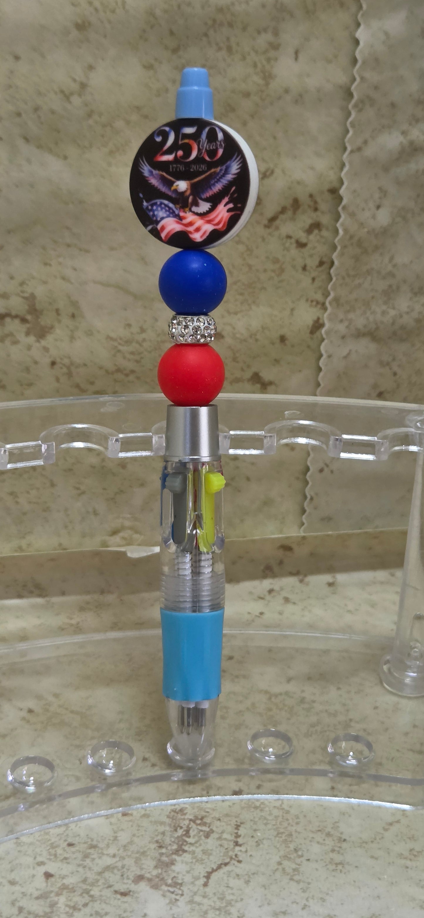 4 different colors click pen with red white and blue beads and a round 250 with an eagle and flag topper