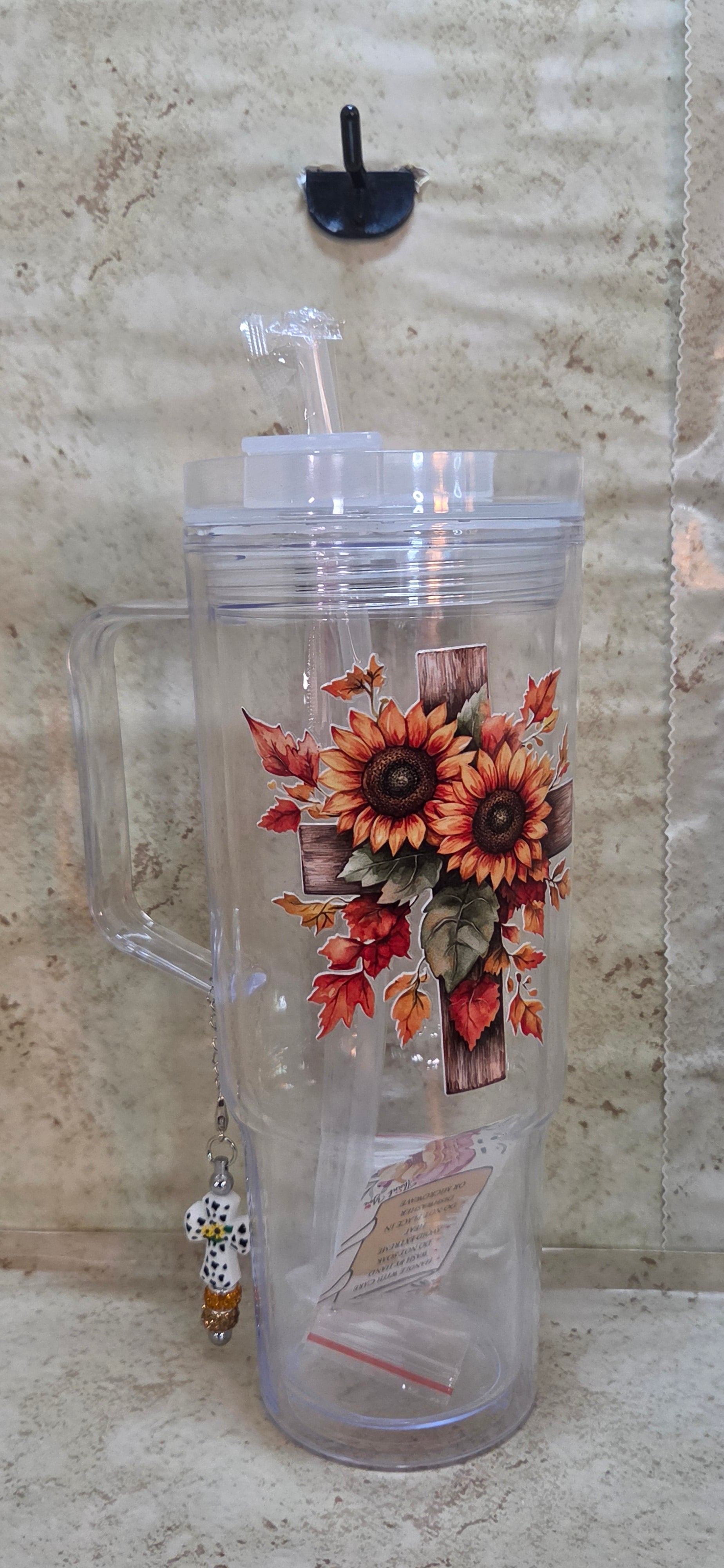 Plastic 40oz tumbler with wooden cross with sunflowers design includes straw and 2 plugs and a black and white cross charm with sparkly orange and brown beads