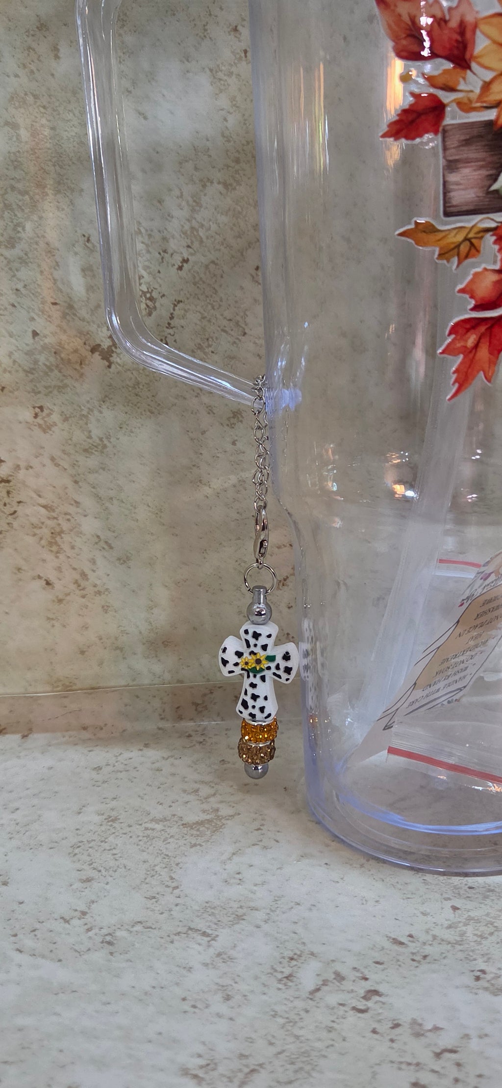 Plastic 40oz tumbler with wooden cross with sunflowers design includes straw and 2 plugs and a black and white cross charm with sparkly orange and brown beads