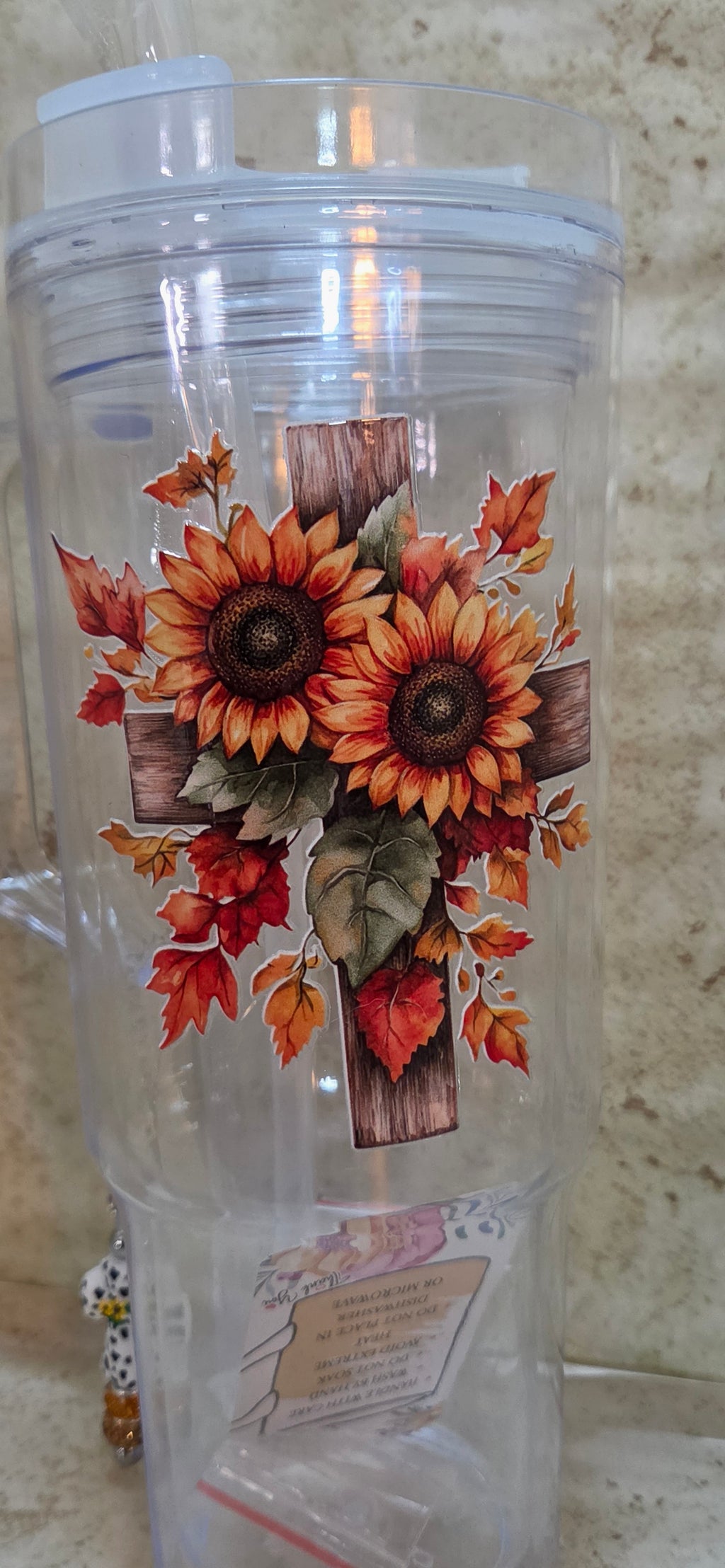 Plastic 40oz tumbler with wooden cross with sunflowers design includes straw and 2 plugs and a black and white cross charm with sparkly orange and brown beads