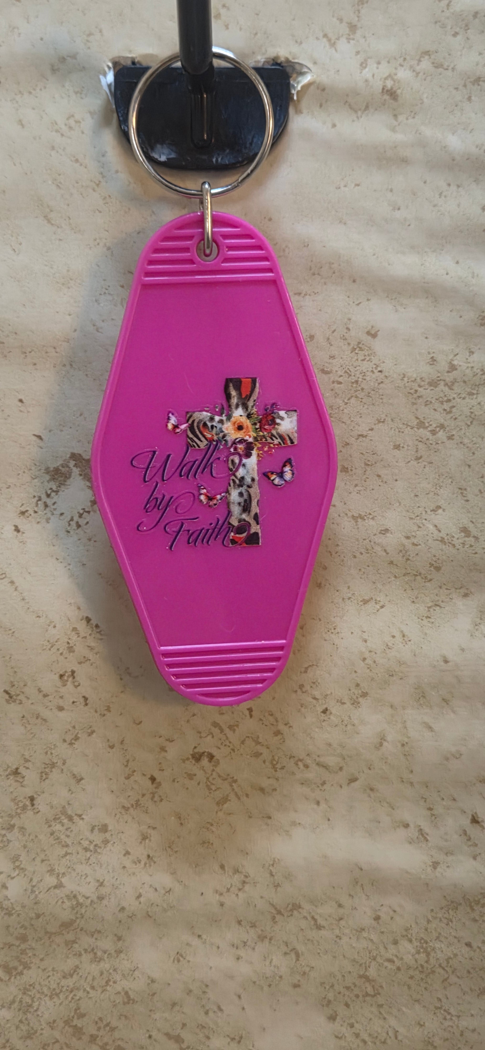 Pink replica of a motel keychain with a floral designed cross and butterflies says Walk by Faith